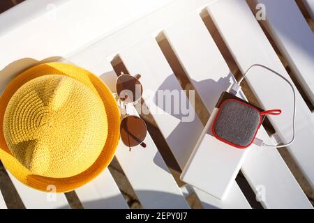 Le haut-parleur portable de musique est chargé depuis la banque d'énergie via usb sur une chaise longue près de la piscine avec des accessoires de plage. Toujours en contact, gadgets de voyage, e Banque D'Images