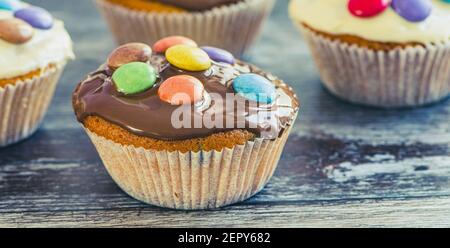 gros plan d'un muffin avec un revêtement et des lentilles au chocolat sur fond en bois Banque D'Images