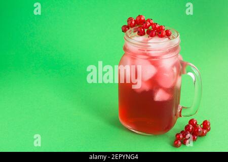 Limonade froide ou cocktail avec des raisins de Corinthe rouges dans le verre sur fond vert. Gros plan. Copier l'espace. Banque D'Images