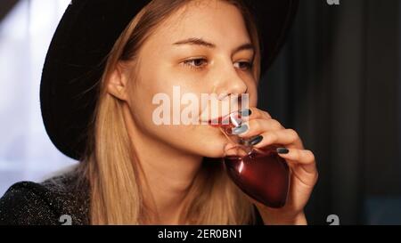 Belle jeune femme buvant la potion d'amour d'une bouteille dedans la forme d'un cœur Banque D'Images