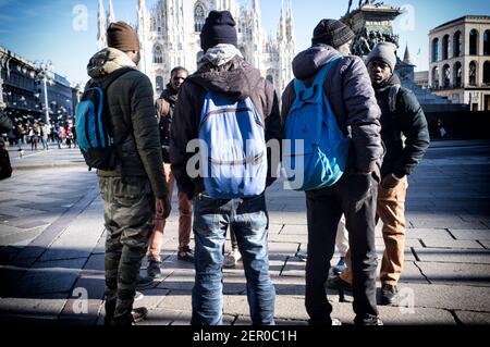 Milan, Italie - 11 janvier 2019: Hommes noirs africains, hommes, immigrants debout sur la place du Dôme de Milan, avec des touristes Banque D'Images