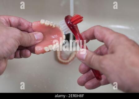 Nettoyage de la prothèse avec une brosse dans l'évier avec de l'eau courante Banque D'Images