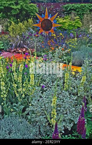 Voici la décoration en mosaïque du soleil avec des bordures de fleurs colorées dans un jardin Banque D'Images