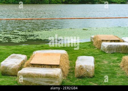 Sièges et tables faits de balles de paille pour l'événement et la fête posés sur la pelouse. Pailles de chaume décorées pour s'asseoir dans la campagne. Mobilier fait Banque D'Images