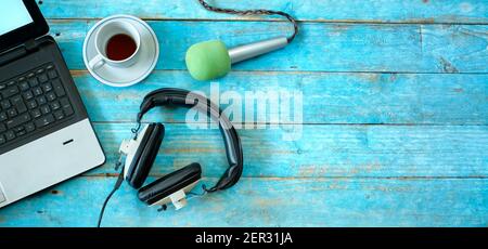 Concept de musique, podcast ou livre audio, plat avec casque, microphone, café et ordinateur portable sur table en bois bleu Banque D'Images