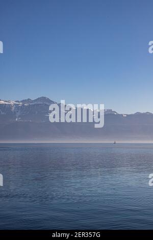 Un bateau sur le lac brumeux, le lac Léman et les Alpes vus de Lausanne, Suisse Banque D'Images