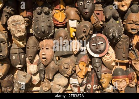 Masques africains traditionnels suspendus pour la vente dans une impasse du marché. Banque D'Images