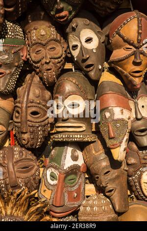 Masques africains traditionnels suspendus pour la vente dans une impasse du marché. Banque D'Images