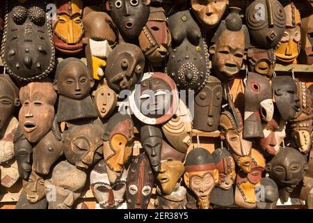 Masques africains traditionnels suspendus pour la vente dans une impasse du marché. Banque D'Images