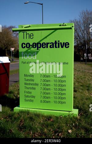 Un panneau indiquant les heures d'ouverture d'un mini-supermarché Co-operative Food, Woodloes Park Estate, Warwick, Royaume-Uni Banque D'Images