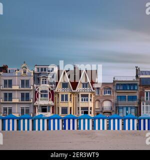 Des cabanes de plage colorées à Dunkerque contre des bâtiments historiques de bord de mer Banque D'Images