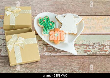 Biscuits en forme de fleur, de cactus et d'ange, à côté de petites boîtes-cadeaux. Banque D'Images