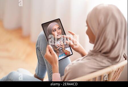 Femme effectuant un appel vidéo avec un ami musulman à l'aide d'un smartphone Banque D'Images