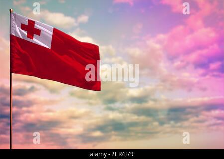 Le drapeau des Tonga se déforme avec la place pour votre texte sur fond ciel nuageux et coloré. Banque D'Images