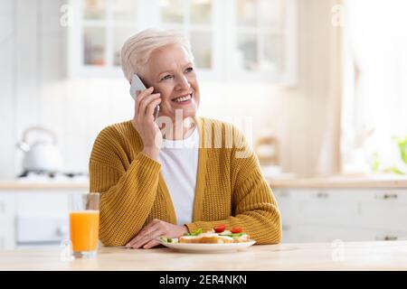 Belle femme âgée déjeuner et parler au téléphone Banque D'Images