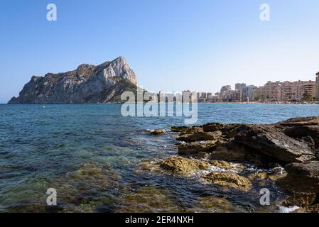Vue depuis les rochers de la côte avec la plage urbaine de Calpe et le crag en arrière-plan, Alicante, Espagne Banque D'Images
