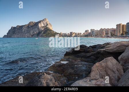 Vue depuis les rochers de la côte avec la plage urbaine de Calpe et le crag en arrière-plan, Alicante, Espagne Banque D'Images