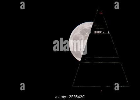 28 février 2021, Hessen, Francfort-sur-le-main : la pleine lune est au-dessus du sommet du Messeturm à Francfort. Les températures redescendent en dessous du point de congélation, surtout la nuit. Photo : Boris Roessler/dpa Banque D'Images