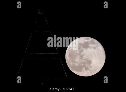 28 février 2021, Hessen, Francfort-sur-le-main : la pleine lune est au-dessus du sommet du Messeturm à Francfort. Les températures redescendent en dessous du point de congélation, surtout la nuit. Photo : Boris Roessler/dpa Banque D'Images