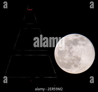 28 février 2021, Hessen, Francfort-sur-le-main : la pleine lune est au-dessus du sommet du Messeturm à Francfort. Les températures redescendent en dessous du point de congélation, surtout la nuit. Photo : Boris Roessler/dpa Banque D'Images