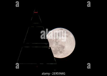 28 février 2021, Hessen, Francfort-sur-le-main : la pleine lune est au-dessus du sommet du Messeturm à Francfort. Les températures redescendent en dessous du point de congélation, surtout la nuit. Photo : Boris Roessler/dpa Banque D'Images