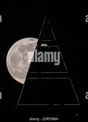 28 février 2021, Hessen, Francfort-sur-le-main : la pleine lune est au-dessus du sommet du Messeturm à Francfort. Les températures redescendent en dessous du point de congélation, surtout la nuit. Photo : Boris Roessler/dpa Banque D'Images