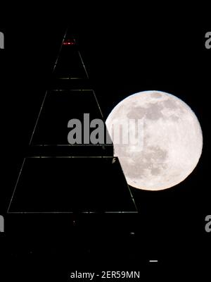 28 février 2021, Hessen, Francfort-sur-le-main : la pleine lune est au-dessus du sommet du Messeturm à Francfort. Les températures redescendent en dessous du point de congélation, surtout la nuit. Photo : Boris Roessler/dpa Banque D'Images