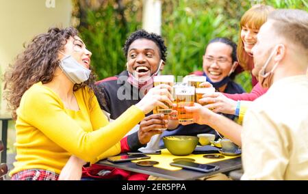 Groupe heureux d'amis multiraciaux avec masque de boire et Toaster la bière au bar-restaurant de la brasserie - Nouveau style de vie normal concept de l'amitié Banque D'Images