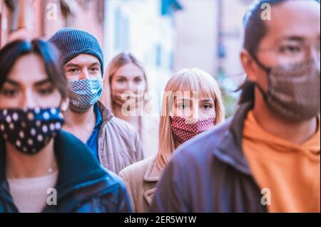 Groupe d'amis marchant ensemble en portant un masque facial au centre-ville - Nouveau concept de style de vie normal avec les jeunes couverts par Masque de protection - mise au point o Banque D'Images