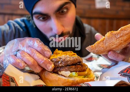 Homme arabe au restaurant mangeant du hamburger Banque D'Images