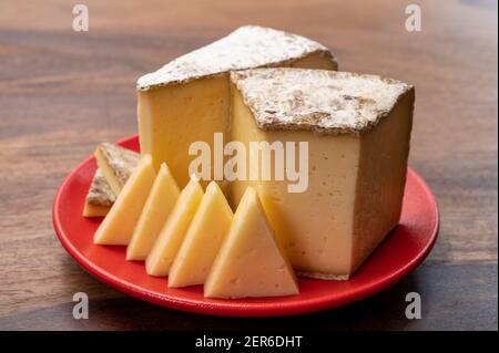 Collection de fromages, tomme de Savoie de Savoie dans les Alpes françaises, fromage de lait de vache doux avec intérieur beige et croûte épaisse gris brunâtre Banque D'Images