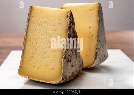 Collection de fromages, tomme de Savoie de Savoie dans les Alpes françaises, fromage de lait de vache doux avec intérieur beige et croûte épaisse gris brunâtre Banque D'Images