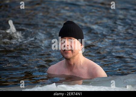 Homme portant un bonnet pendant la baignade d'hiver dans un bassin de glace ou avanto dans le district de Munkkiniemi à Helsinki, en Finlande Banque D'Images