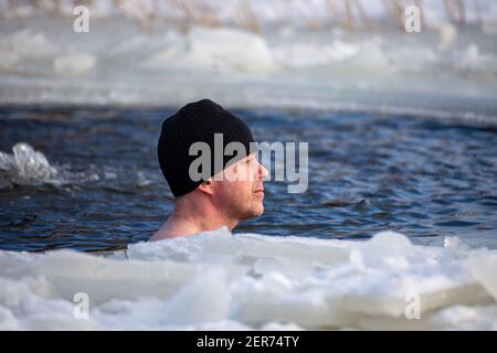 Homme avec bonnet noir hiver nageant à avanto ou trou de glace à Munkkiniemenranta Beach, Helsinki, Finlande Banque D'Images