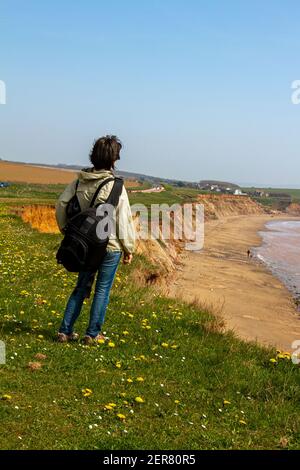 Photo verticale d'une femme randonneur avec un sac à dos comme Elle se tient seule sur les falaises de l'Isle De Wight et de profiter du paysage de ce beau Banque D'Images