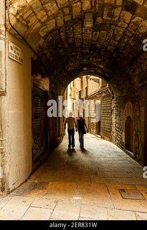 Barcelone, Espagne 05-01-2010: Un couple tenant des mains dans le Carrer de la Volta del Remei, ruelle étroite en pierre avec des arcades historiques et des passages dans le Banque D'Images