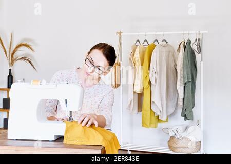 Femme couture sur machine à coudre dans un petit studio. Atelier de mode, artisanat sur mesure, vêtements faits main, Industrie, concept. Mode lent.consommation consciente Banque D'Images