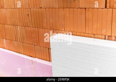 Isolation thermique externe d'un bâtiment sur un chantier de construction avec des feuilles de polystyrène. Économie d'énergie dans la construction d'une maison familiale. Banque D'Images