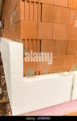 Isolation thermique externe d'un bâtiment sur un chantier de construction avec des feuilles de polystyrène. Économie d'énergie dans la construction d'une maison familiale. Banque D'Images