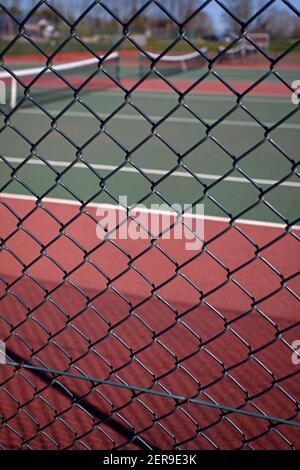 Vue à travers la clôture de chaînette vers les courts de tennis vides. Angleterre Banque D'Images