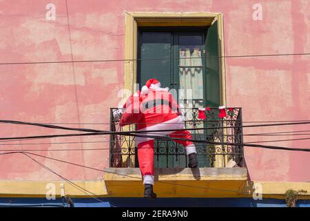 Le Père Noël entre dans une maison par le balcon avec un sac de cadeaux. Banque D'Images