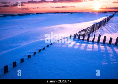 Scène hivernale sous le ciel coloré au coucher du soleil sur la plage enneigée. Jones Beach State Park, long Island NY Banque D'Images