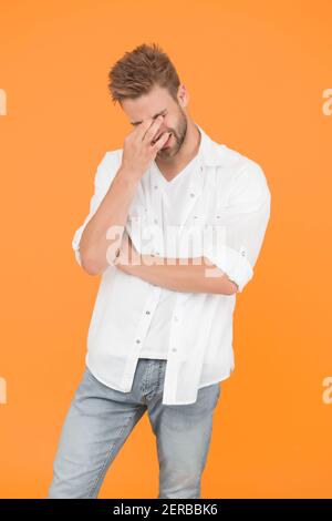 Mal de tête horrible. Bel homme dans un Jean chemise souffrant de douleur de tête. Homme fatigué et stressant fond jaune. Concept de vie stressante. Migraine de tête et spasme. Problèmes de santé. Vie d'affaires. Banque D'Images