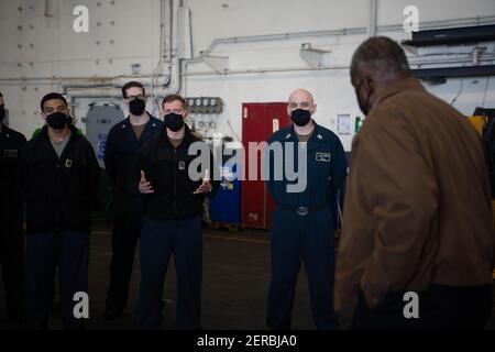 Le secrétaire américain à la Défense, Lloyd J. Austin III, au centre, s'entretient avec les membres du service lors d'une visite au porte-avions de la classe Nimitz USS Nimitz à homeport, à la base navale de San Diego le 25 février 2021 à San Diego, en Californie. Banque D'Images