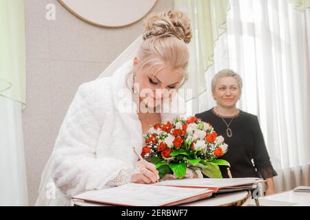 Jolie mariée d'apparence blonde européenne présente une signature sur le mariage consentant. Bélarus, région de Minsk - 23 janvier 202 Banque D'Images