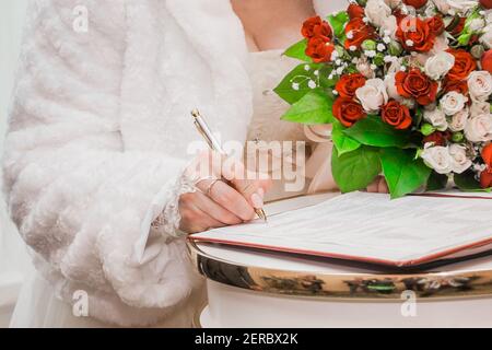 La main de la mariée met le stylo de signature sur le consentement du mariage à la vue rapprochée du mariage. Banque D'Images