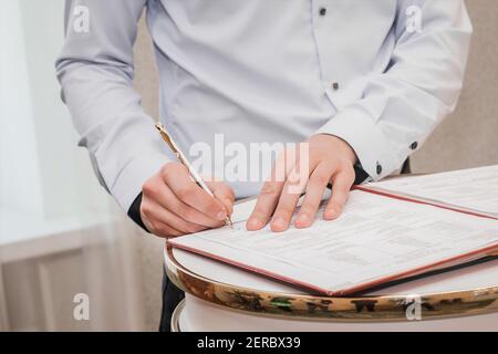 Les mains du petit ami du témoin dans la chemise mettent la signature sur le mariage gros plan. Banque D'Images