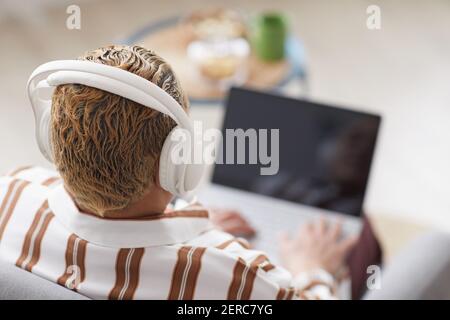 Vue en grand angle chez une femme moderne qui porte un casque tout en utilisant un ordinateur portable à la maison, espace de copie Banque D'Images