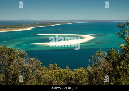 Banc de sable en face de la plage de Tróia au Portugal, entouré d'eaux turquoise avec des bateaux de plaisance amarrés et en arrière-plan la ligne de plage. Banque D'Images