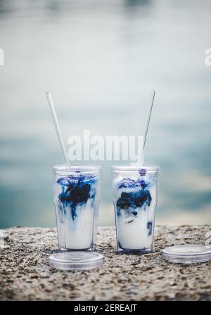 Verre à latte matcha rafraîchissant bleu glacé dans des verres écologiques réutilisables avec pailles en verre sur la côte de la Méditerranée, point sélectif. Prenez une Banque D'Images